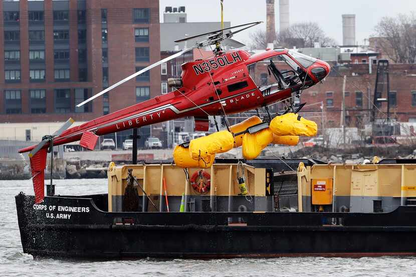 A helicopter is hoisted by crane from the East River onto a barge, Monday, March 12, 2018,...