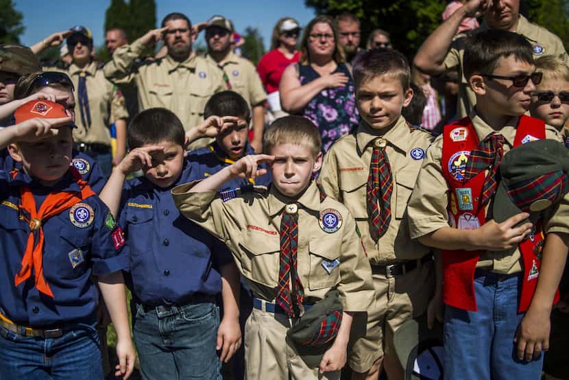 Boy Scouts and Cub Scouts salute during a Memorial Day ceremony in Linden, Mich. The Boy...