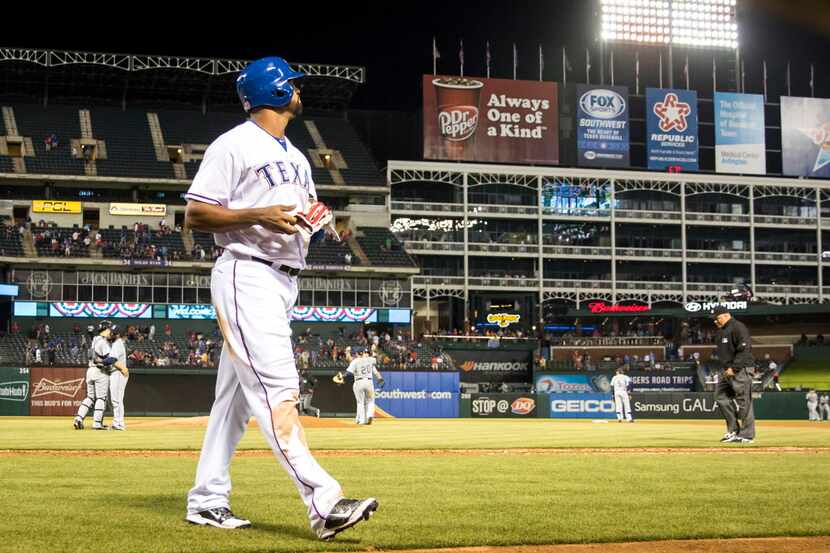 Texas Rangers right fielder Carlos Peguero walks back to the dugout after striking out to...