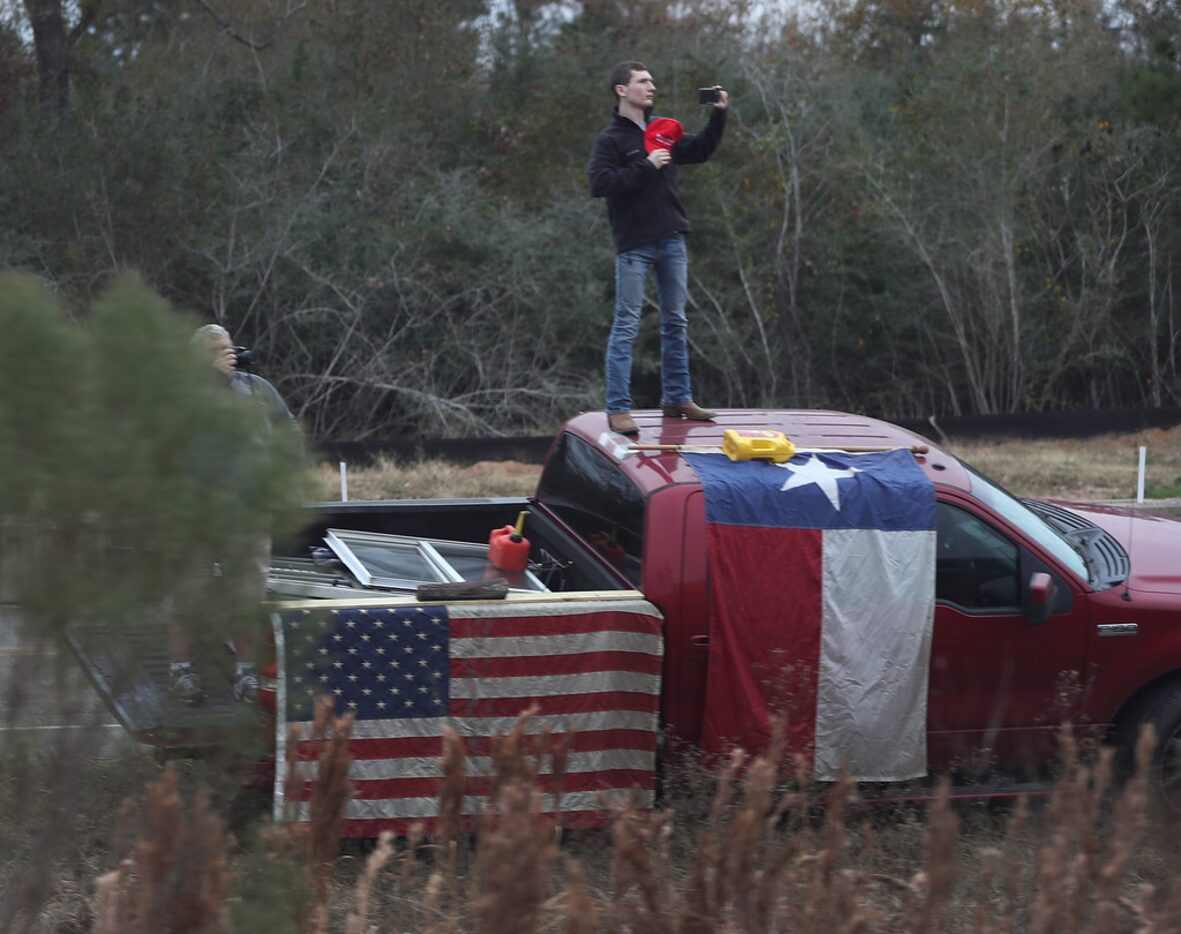 A man stands on a pickup as the train carrying former President George H.W. Bush to his...