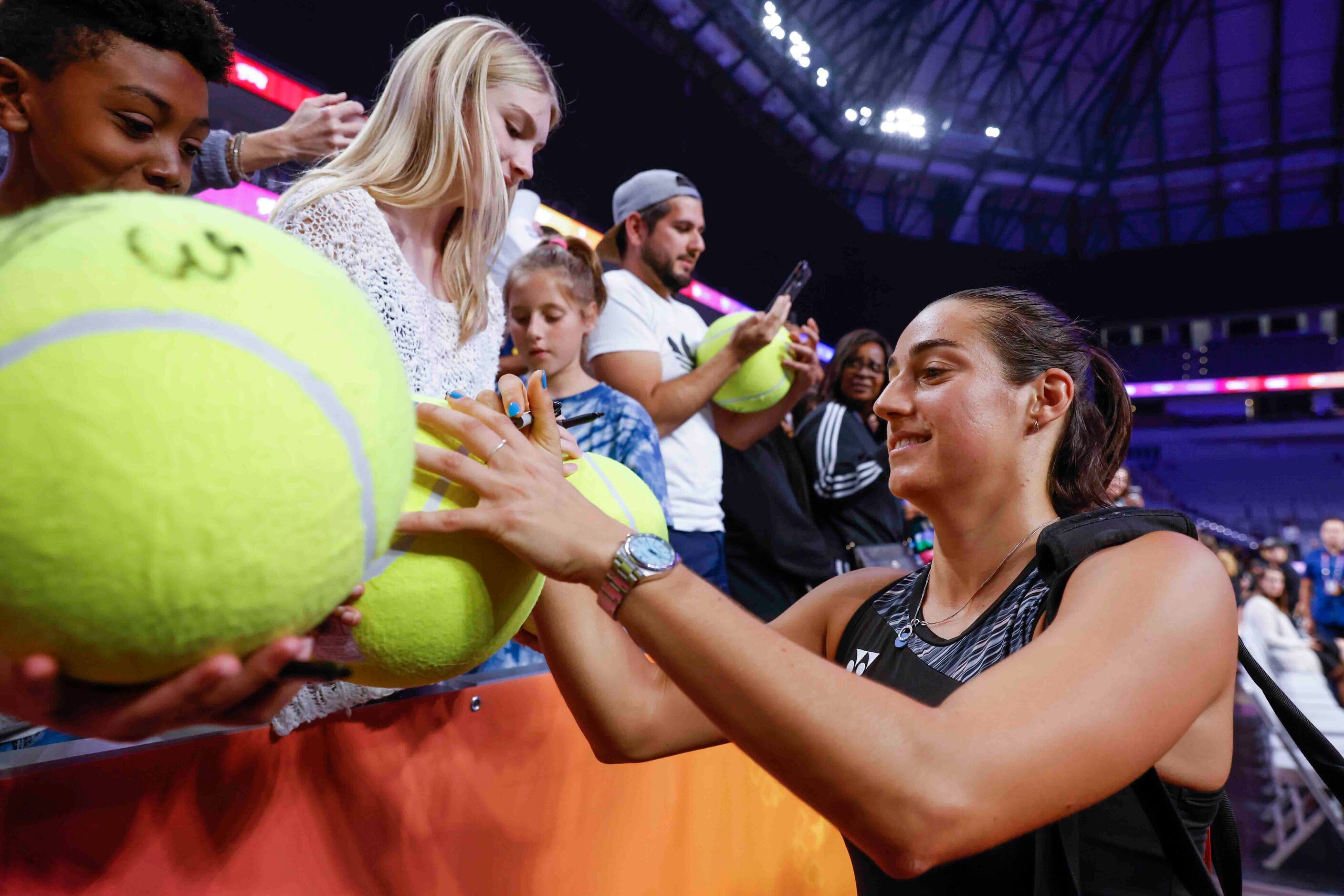 Caroline Garcia of France gives autographs to fans after winning against Coco Gauff of the...