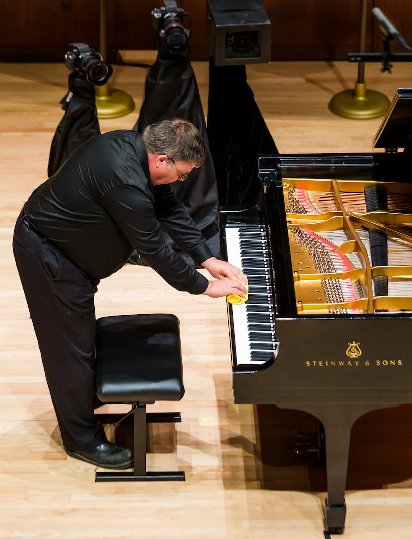 Michael McNicholas wipes off the keys of the piano between performances during the...