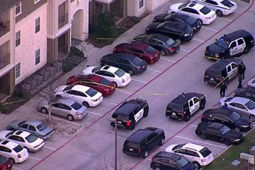 Police crime tape surrounds several cars in an apartment complex in Denton where an...