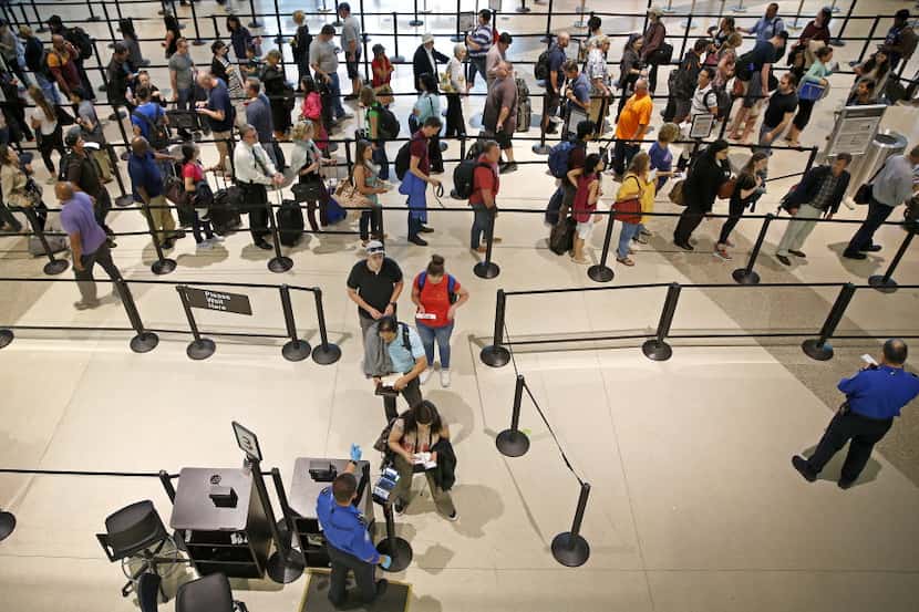 People stand in line to go through the TSA security checkpoint at Dallas Love Field in...