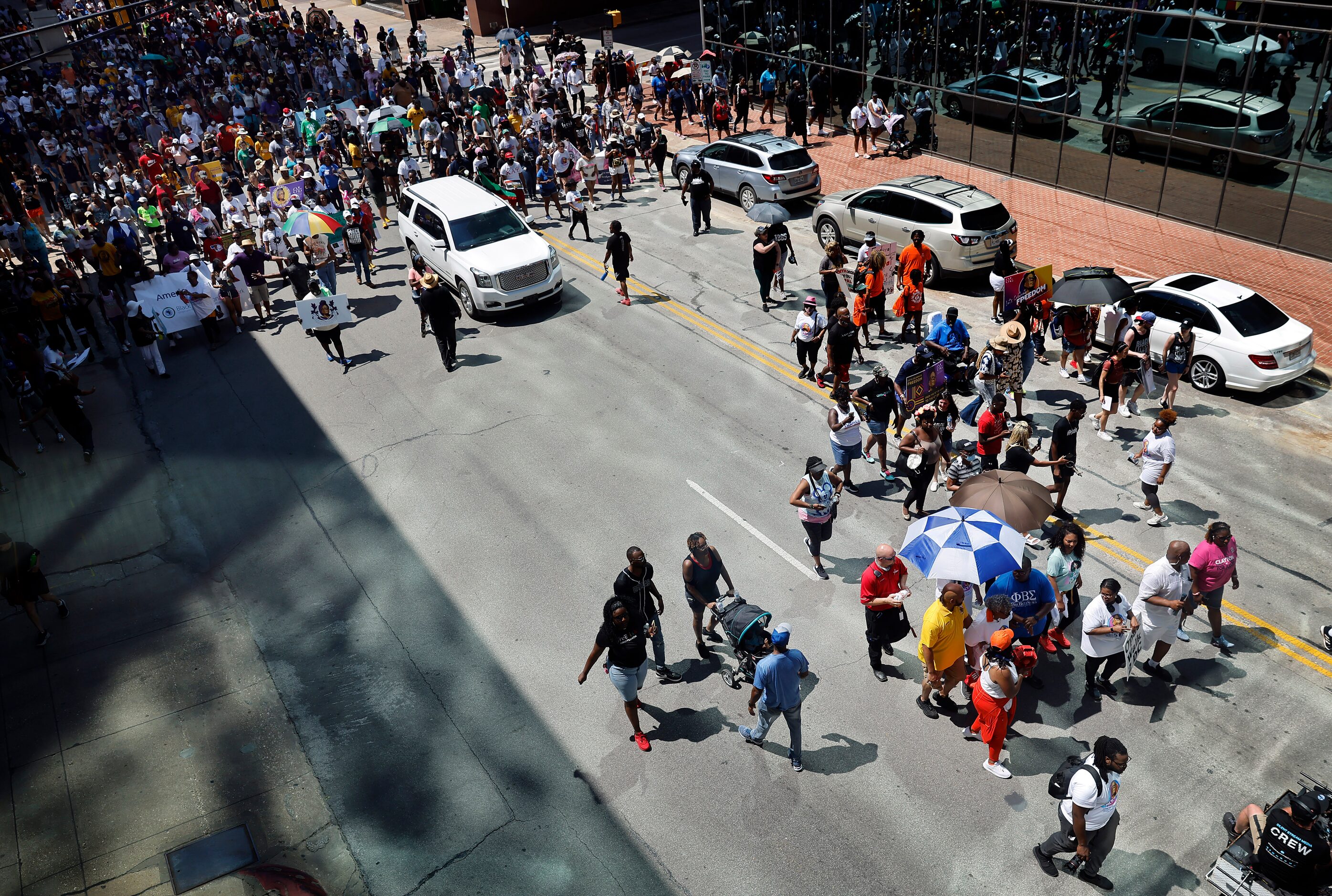 A large group of supporters follow Opal Lee (under umbrellas, right) down Commerce St....