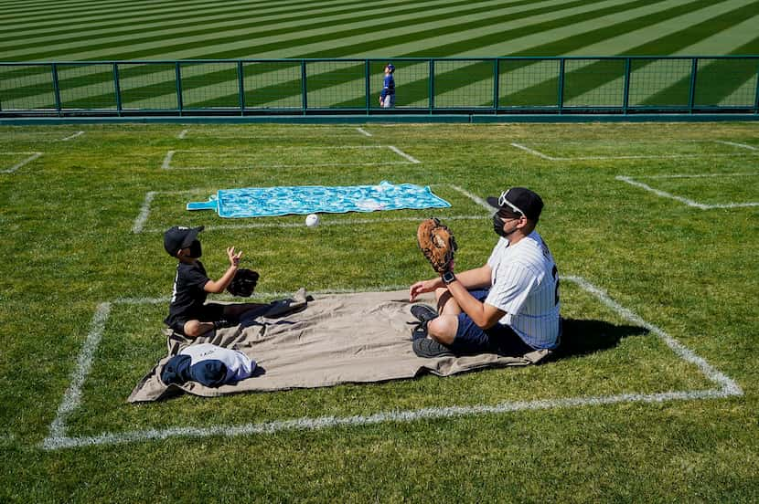 A pair of fans tossed a ball while sitting in a  social distancing square on the outfield...