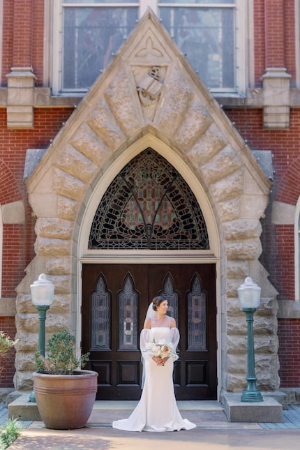 A wedding photo of Morgan Mericle taken in front of First Baptist Dallas' north wall before...