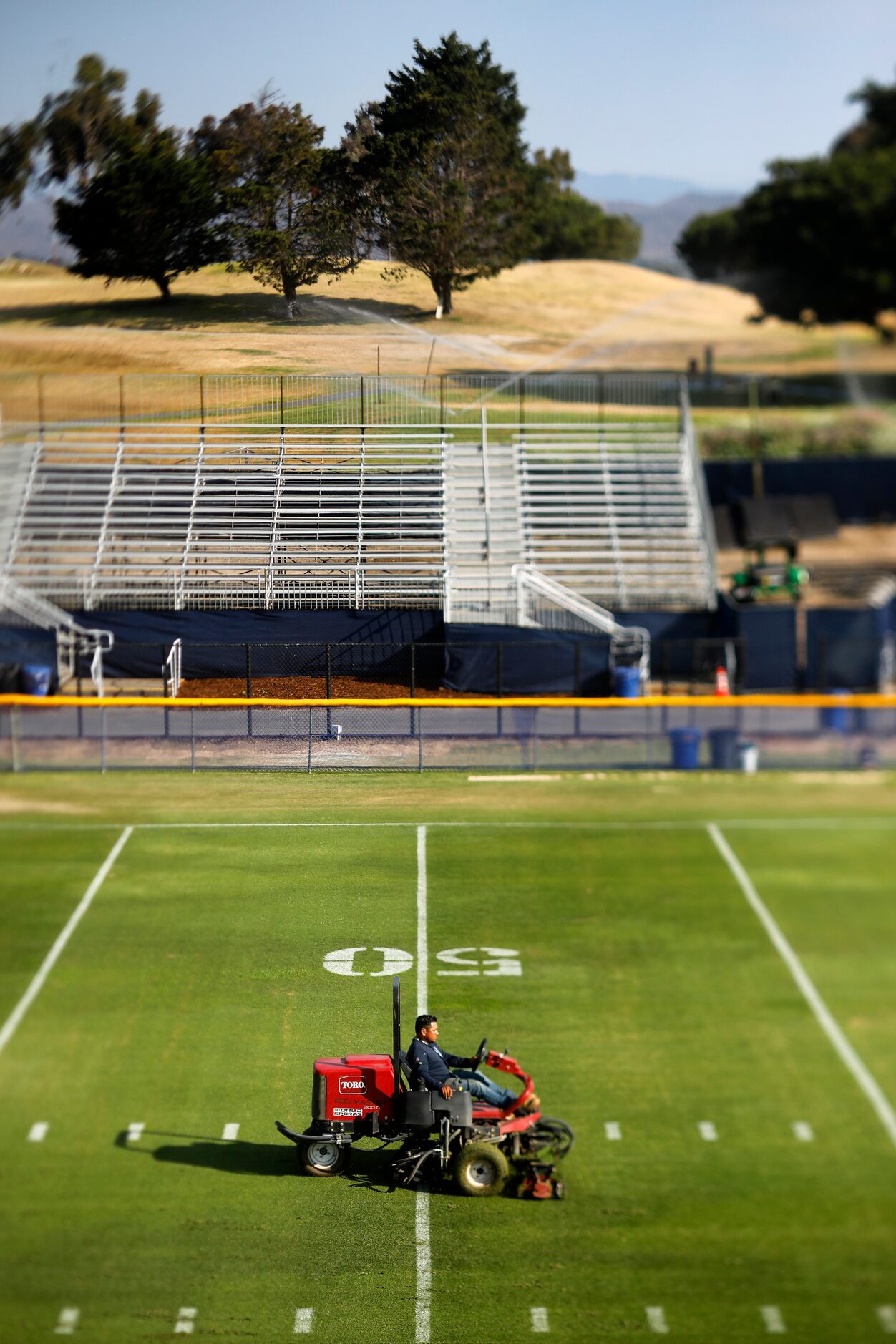 Grounds crewman cut the grass fields in preparation for the teams first practice, Thursday,...