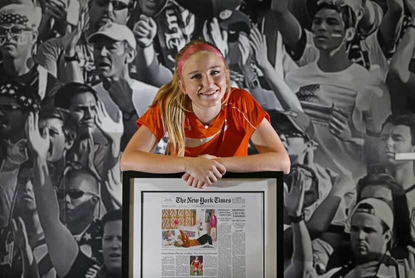 Haley Berg poses for a photograph with the framed cover of The New York Times featuring her...