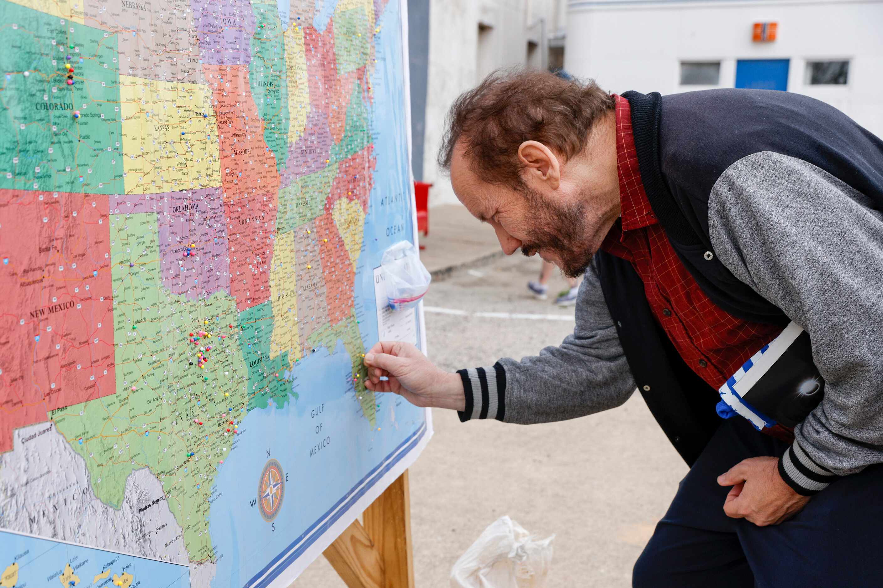 Mike Carlock of Stewart, Florida places a pin onto a map to mark where he’s from before a...