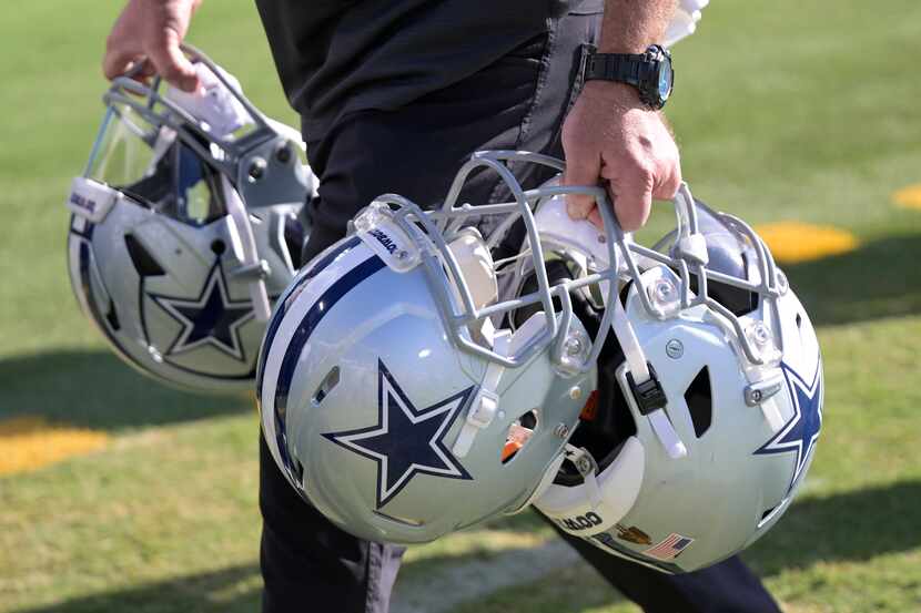 Un miembro del personal de los Cowboys de Dallas saca cascos del campo después de la primera...