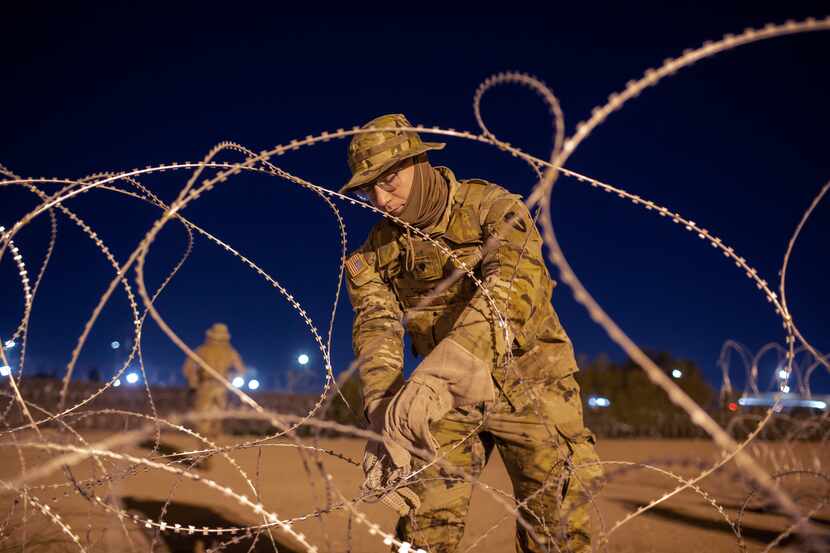 A Texas National Guard soldier ties rows of barbed-wire to be installed near a gate at the...