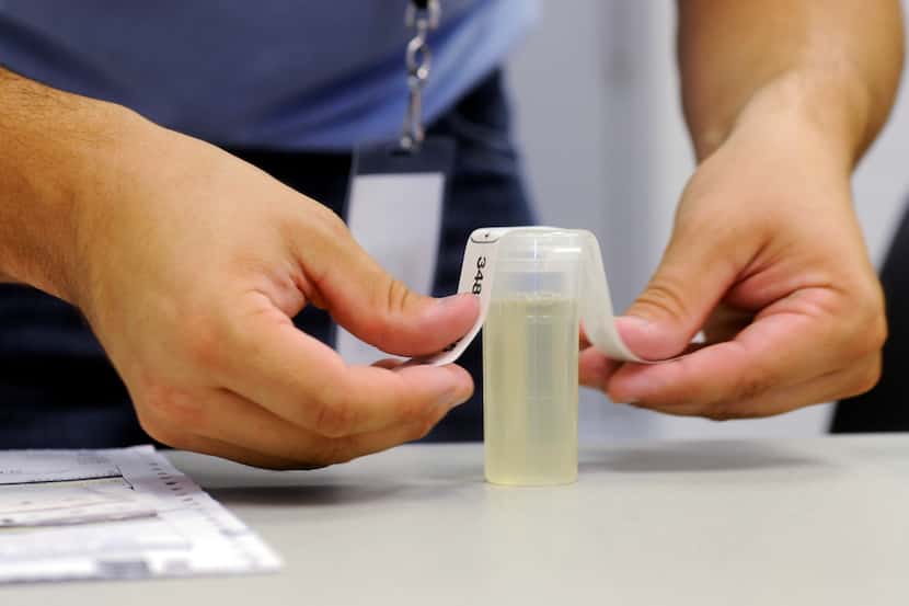 A worker labels a urine specimen vile in September 2011, at Linn State Technical College in...