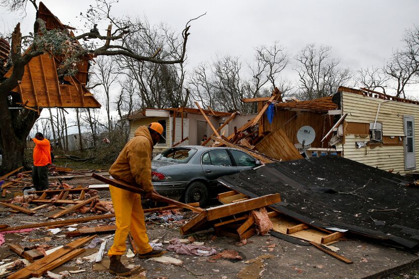 Harry Hobbs, left, takes a break from cleaning up the remnants of the house he is renting...