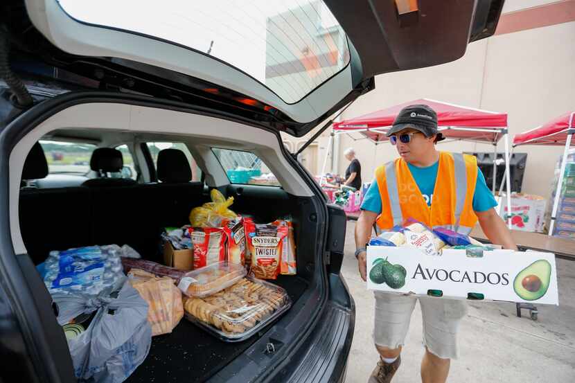 Gallarza loads food into a family's vehicle during Sharing Life's drive-thru pantry event.
