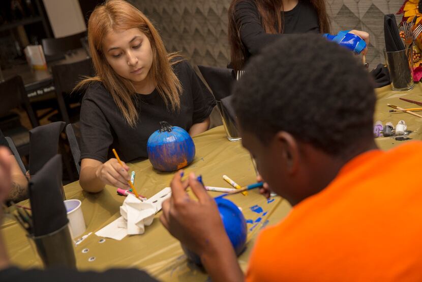 Employees Andrea, 15, left, and Michael, 17, paint pumpkins during an employee Thanksgiving...
