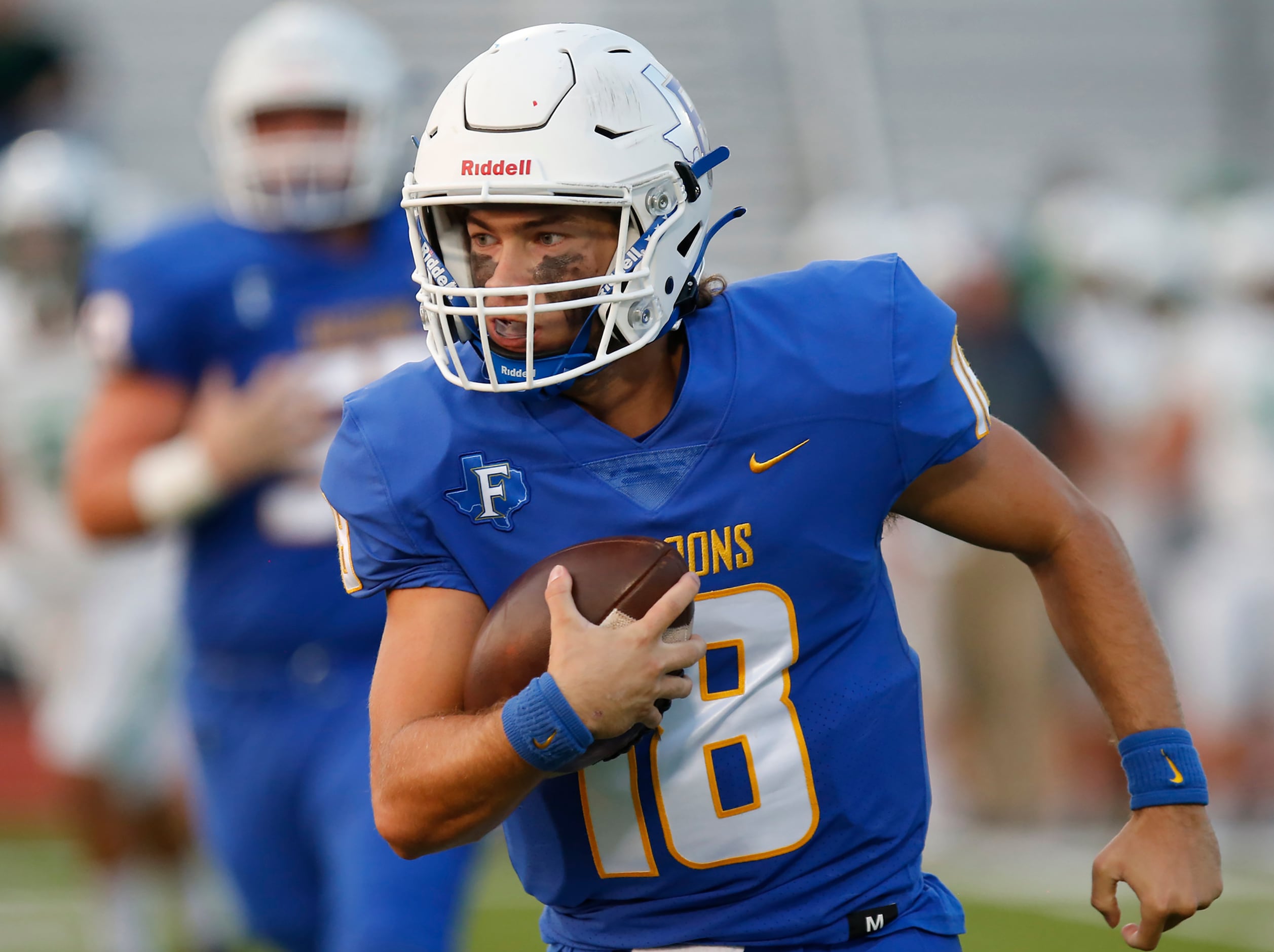 Frisco High School quarterback Wyatt Carson (18) deeps the football on a scramble during the...