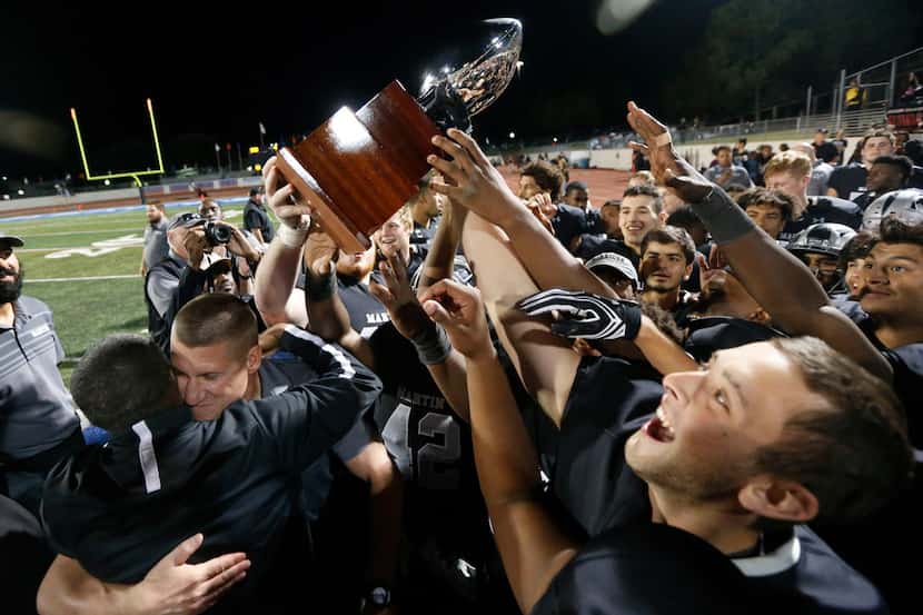 Arlington Martin Players and coach Bob Wager (bottom left) react to their playoff trophy...