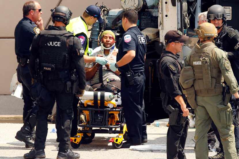 Paramedics strap a handcuffed man onto stretcher after  SWAT team members pulled him from a...