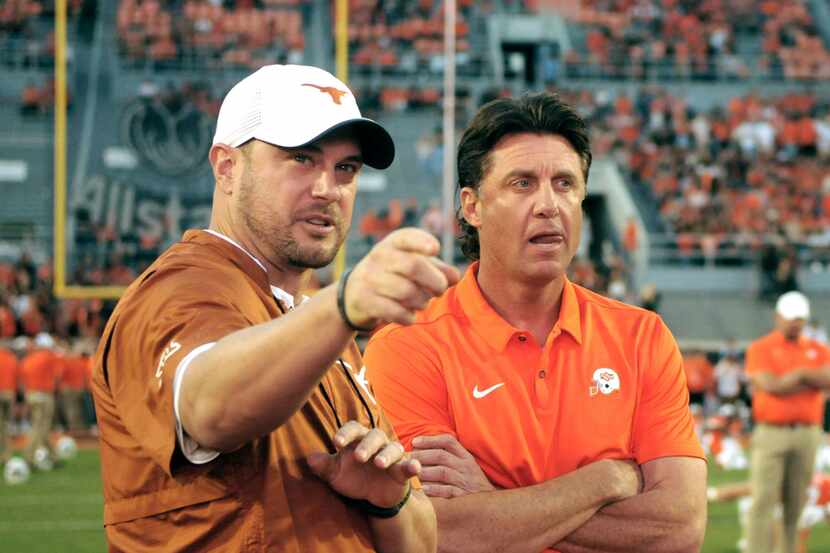 Texas head coach Tom Herman, left, and Oklahoma State head coach Mike Gundy talk prior to an...