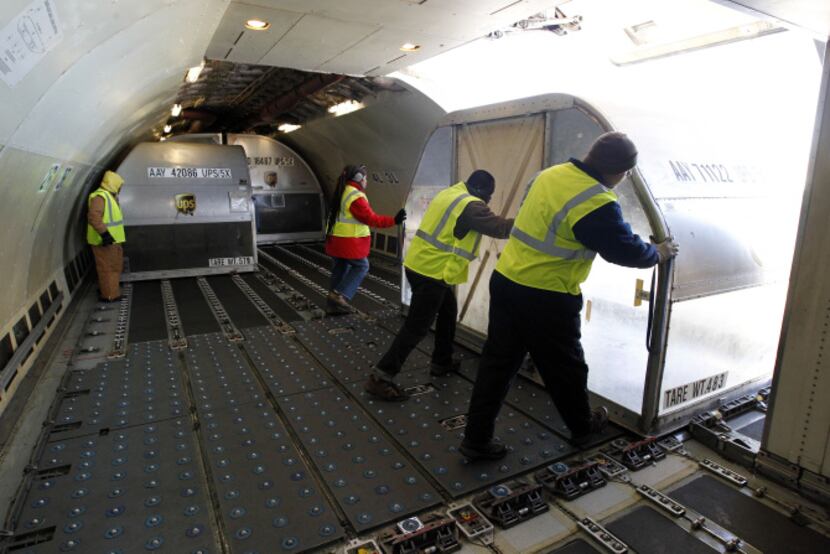Workers move containers from an Airbus A300 to a lift at the UPS cargo sorting facility at...