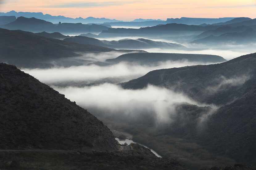 Fog blankets the valley over the Rio Grande river  (seen at the bottom center) that marks...