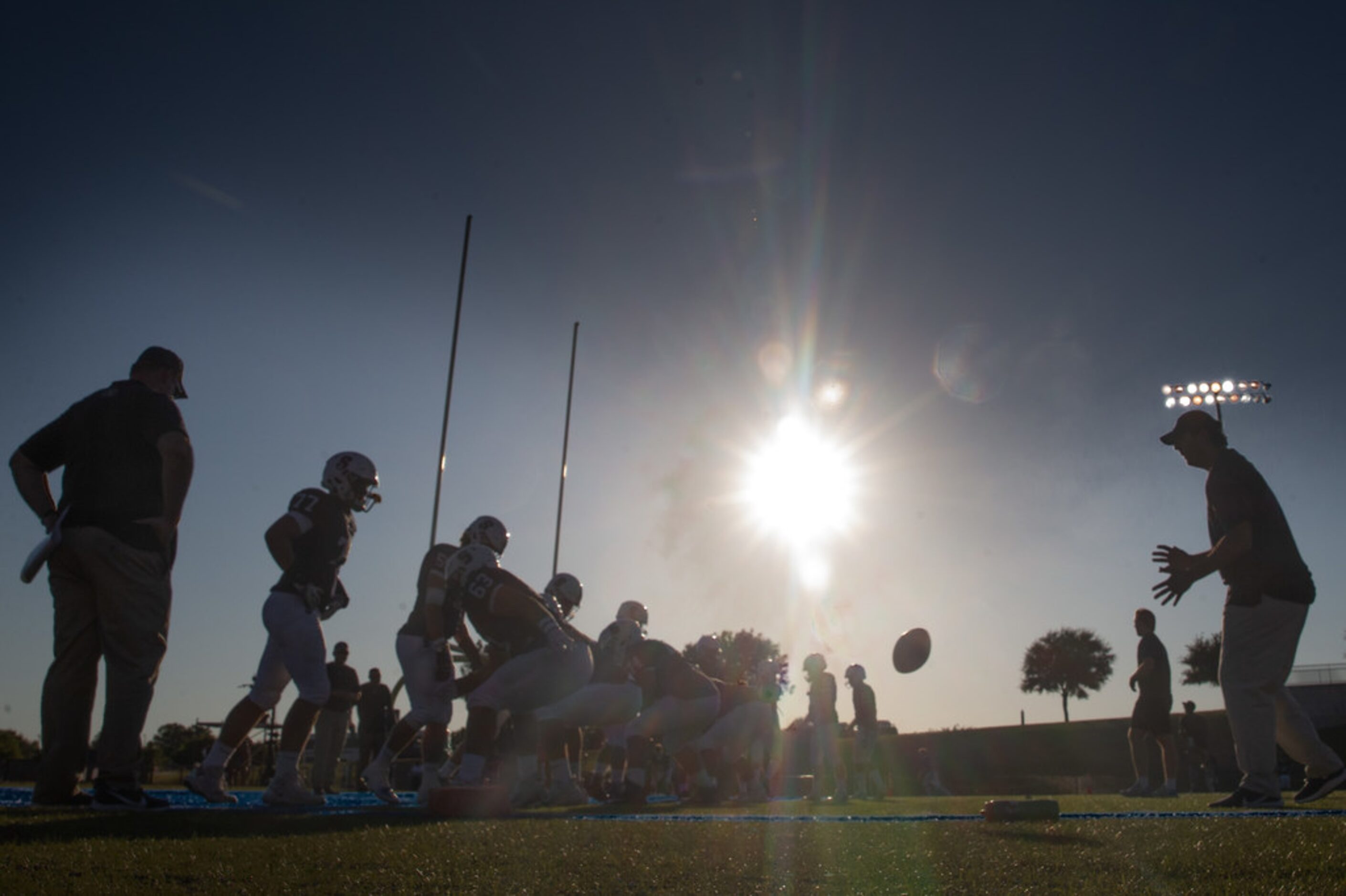 The sun begins to set behind the All Saints' Episcopal School varsity football team as they...