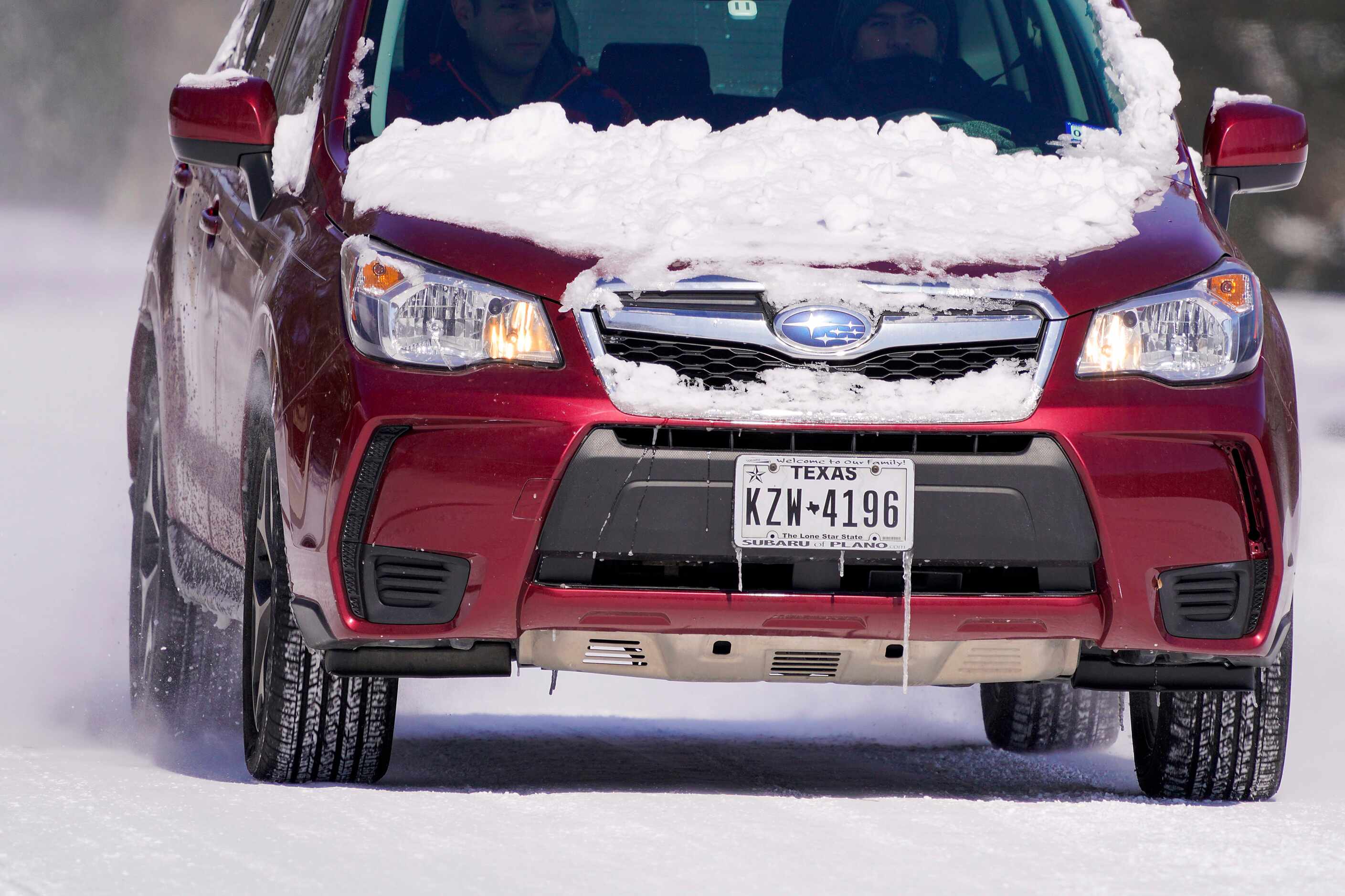 Icicles hang over a Texas license plate on a car after winter storm brought snow and...