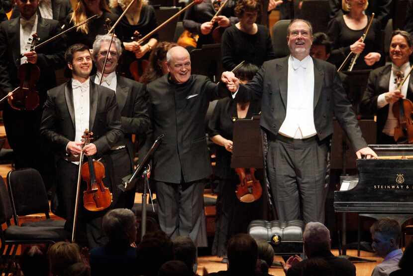 Conductor Hans Graf, left, raises the hand of pianist Garrick Ohlsson, right, after they...