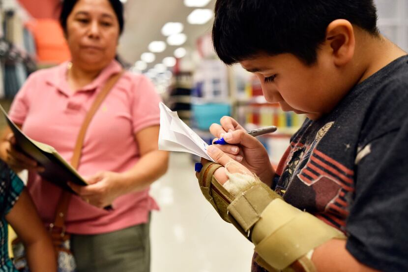 David Arriaga, 9, looked over his checklist while shopping with his mother and sister for...