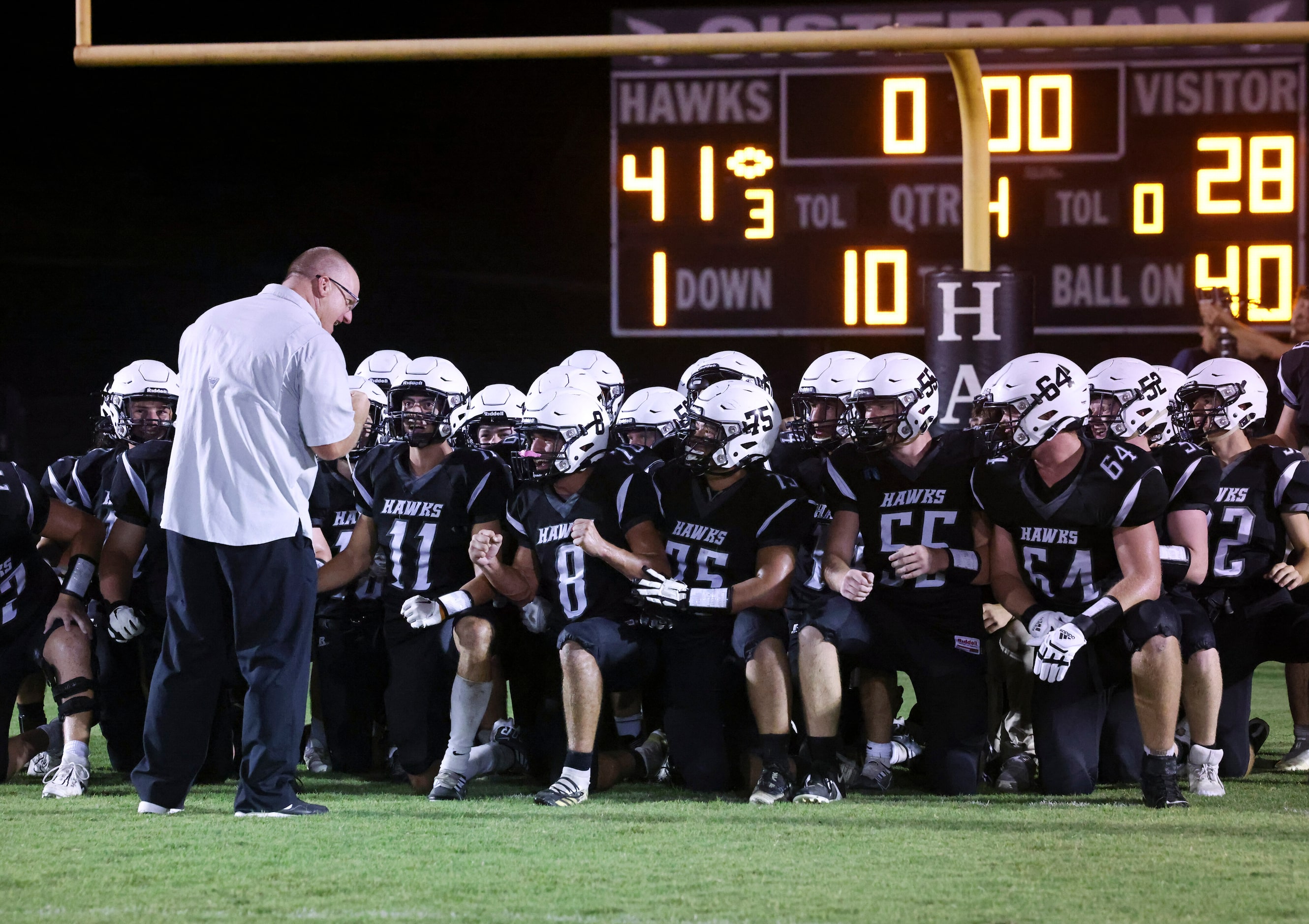 Cistercian Preparatory School players take a knee as head coach James Burk congratulates...