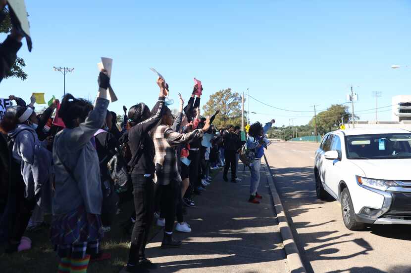 Lake Highlands High School students cheer as cars honk while passing by the group standing...