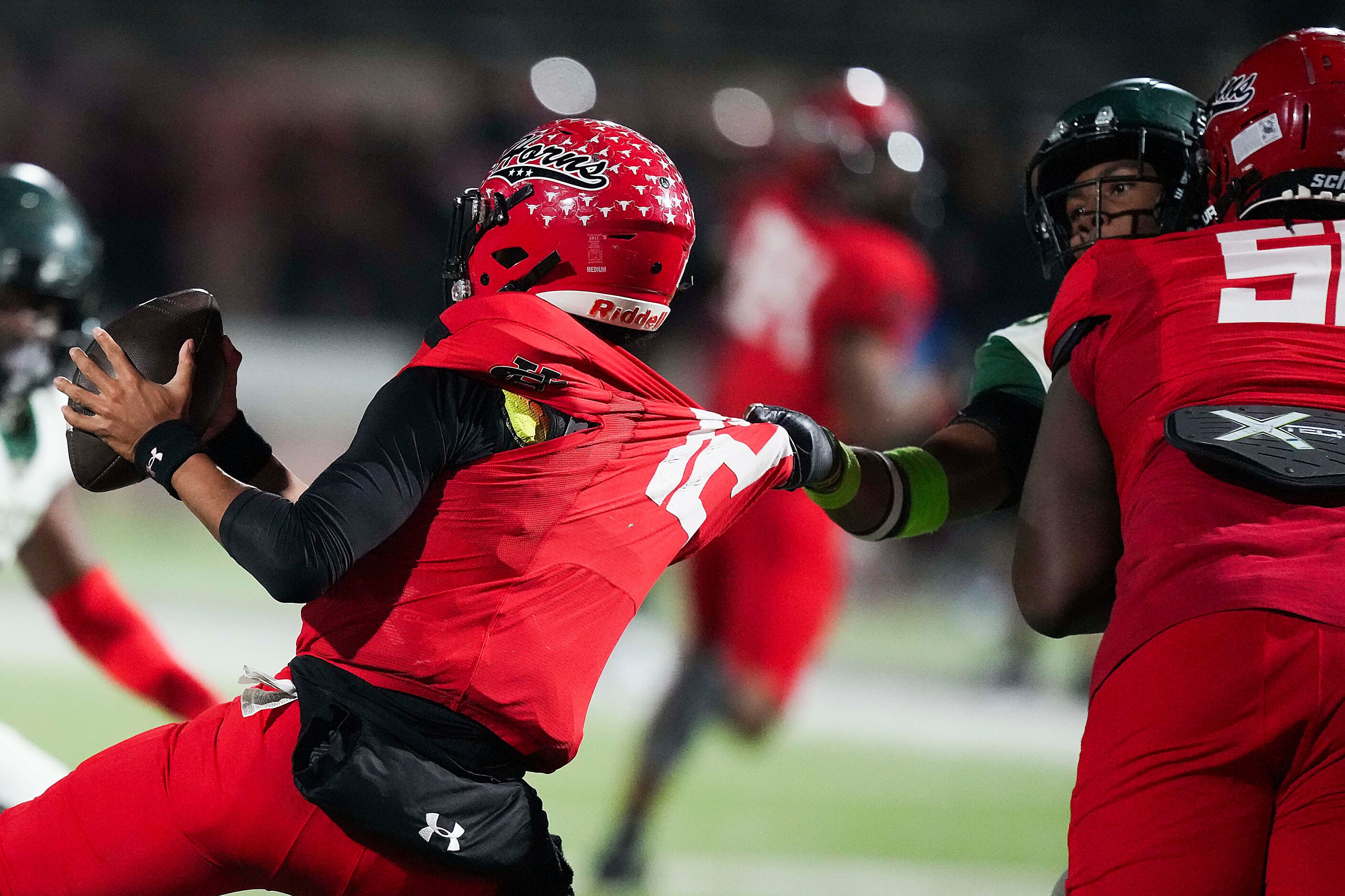 Cedar Hill quarterback Anthony Edwards (12) is pulled backwards by DeSoto defensive lineman...