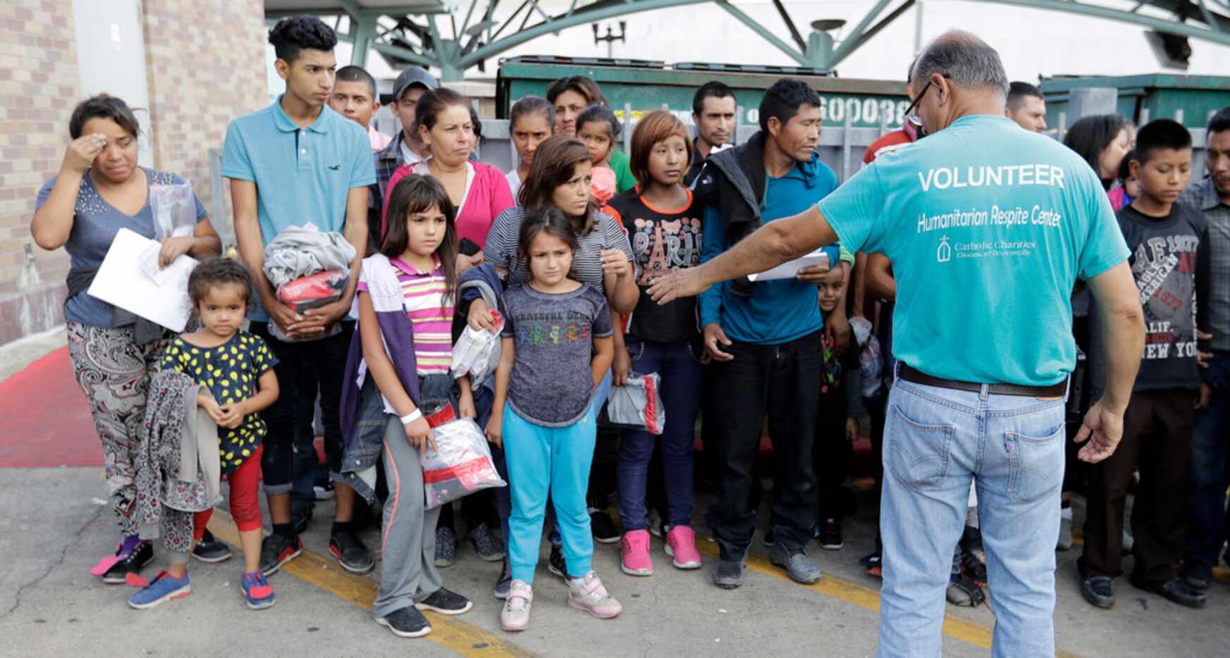 Immigrants are helped by a volunteer at the bus station after they were processed and...