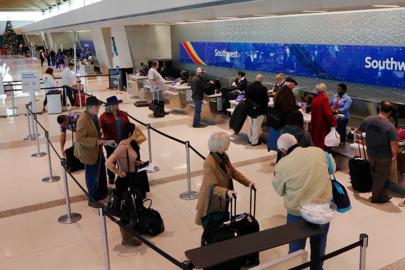 Southwest Airlines passengers wait in line to check in at Dallas Love Field in Dallas,...