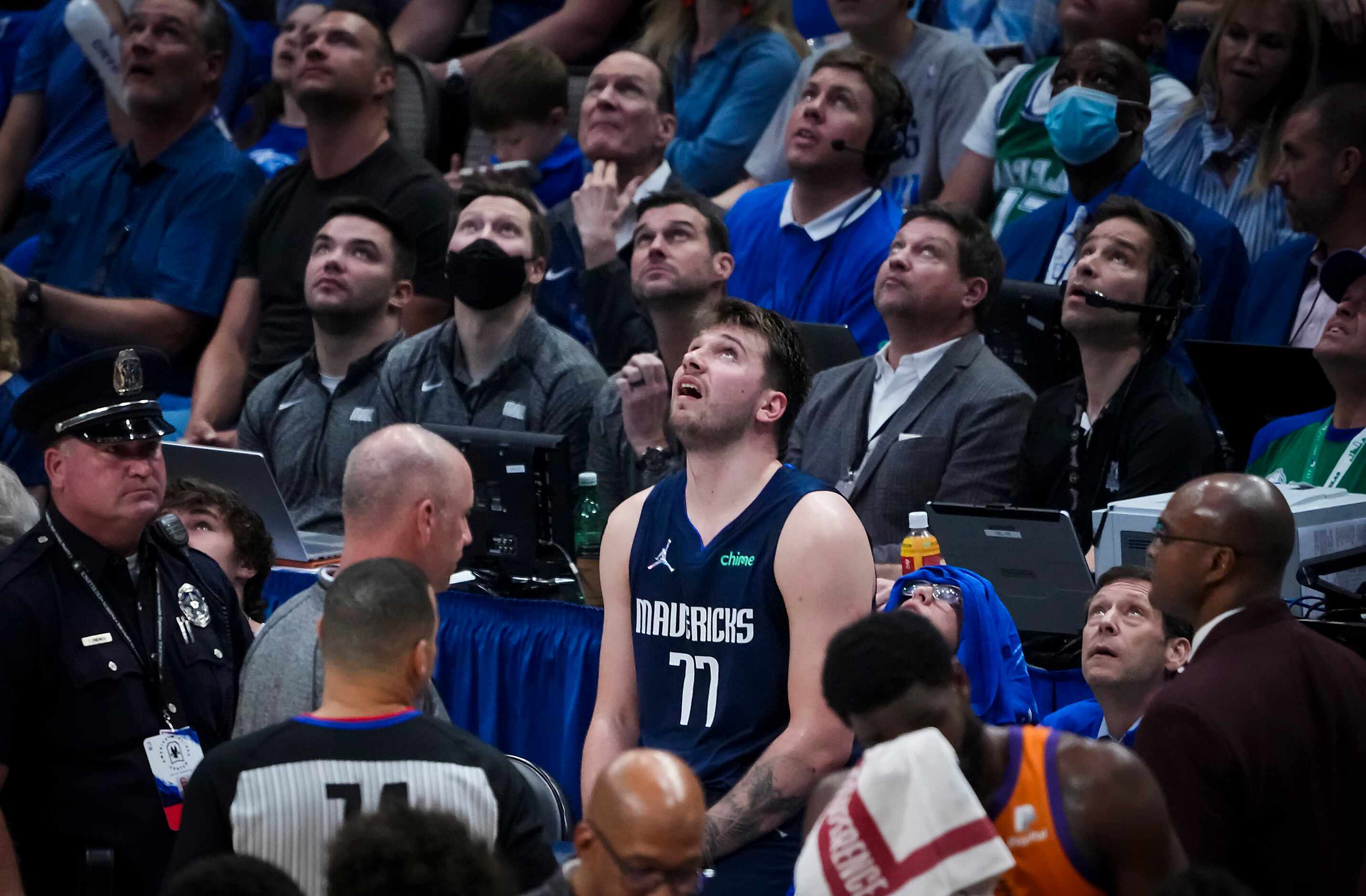 Dallas Mavericks guard Luka Doncic (77) sits on the scorers table and watches a video review...