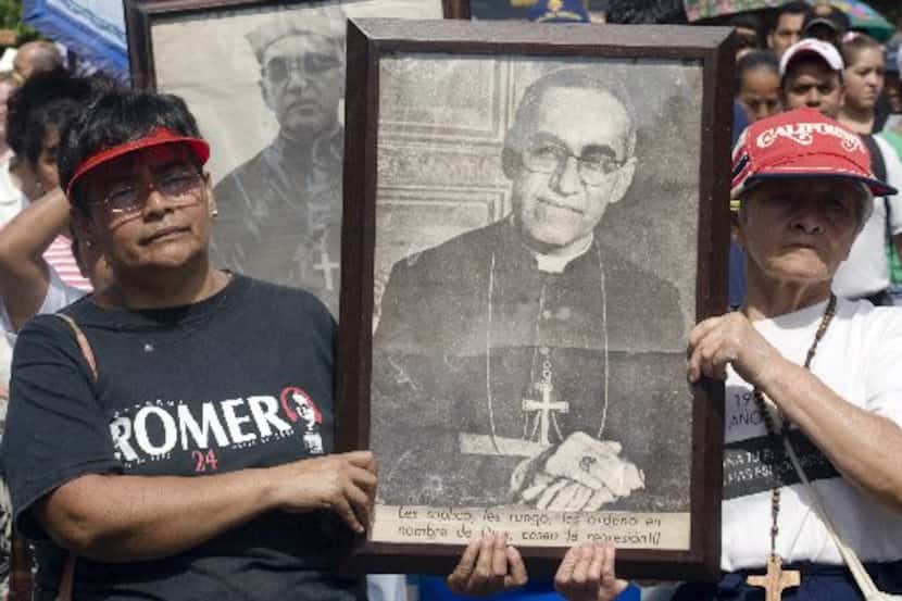 Dos personas llevan una imagen de Monseñor Oscar Arnulfo Romero durante una marcha en San...