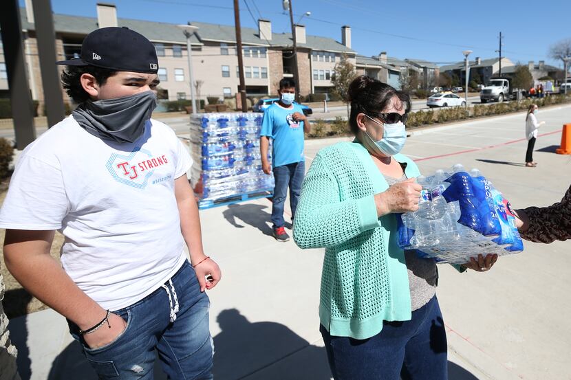 Area resident Belia Ornelas, 50 (right), receives bottled water from the Dallas Office of...