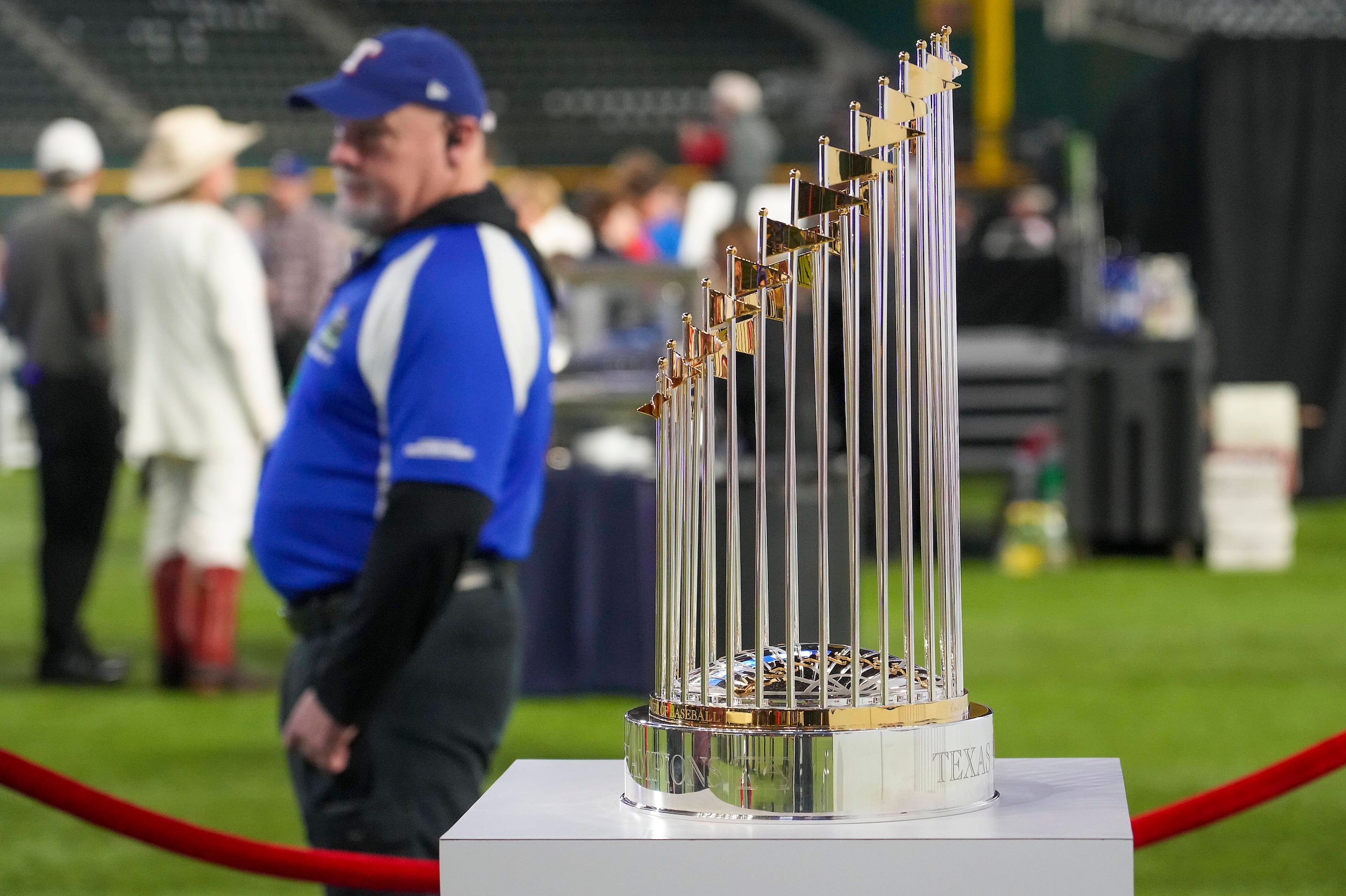 A security guard stands by next to the Commissioner’s Trophy on display during the Texas...