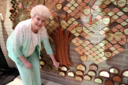  Nita Patrick placing a plaque on the Perpetual Giving Tree. 