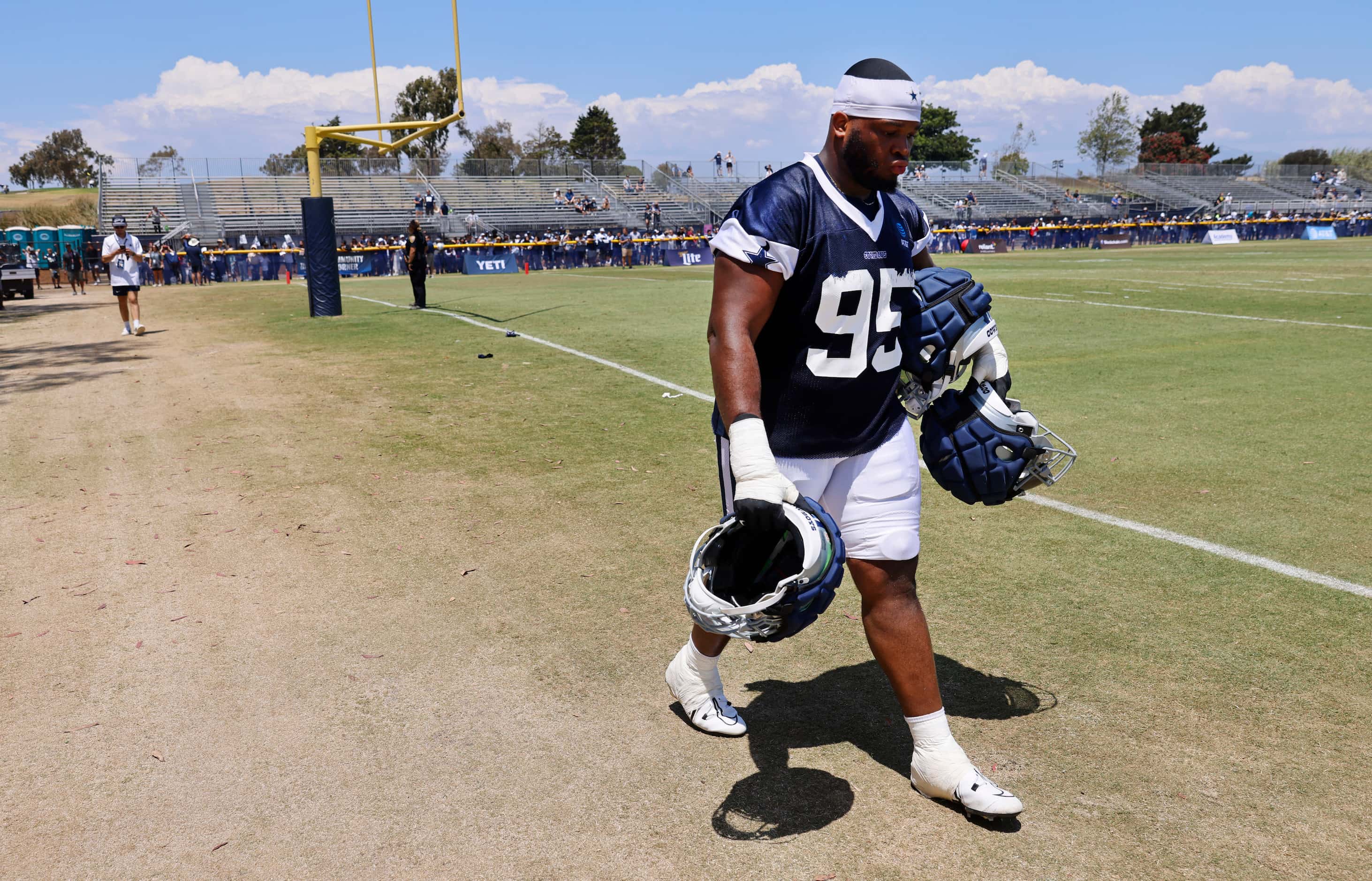 Dallas Cowboys rookie defensive tackle Denzel Daxon (95) carries veteran players helmets to...