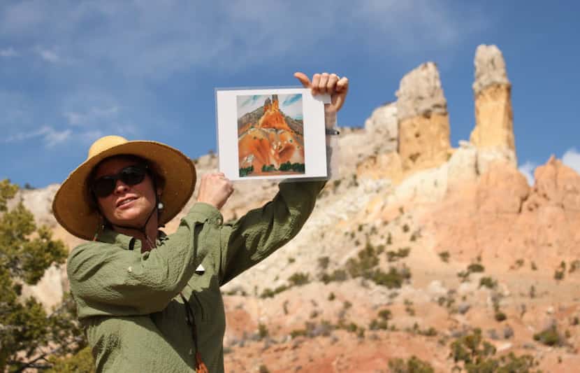 Ghost Ranch tour guide Karen Butts holds up a copy of Georgia O'Keeffe's The Cliff Chimneys,...