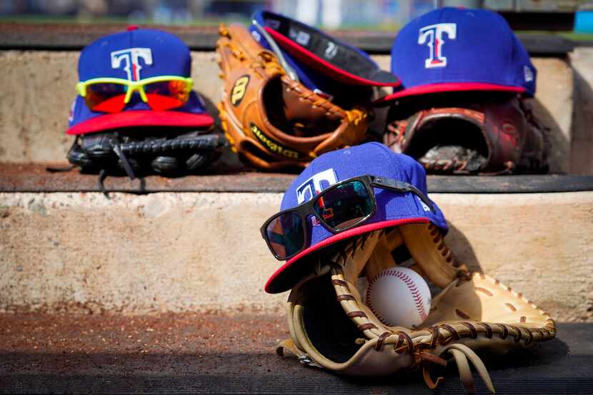 Texas Rangers gloves, hats and glasses rest on a dugout step during the fourth inning of a...