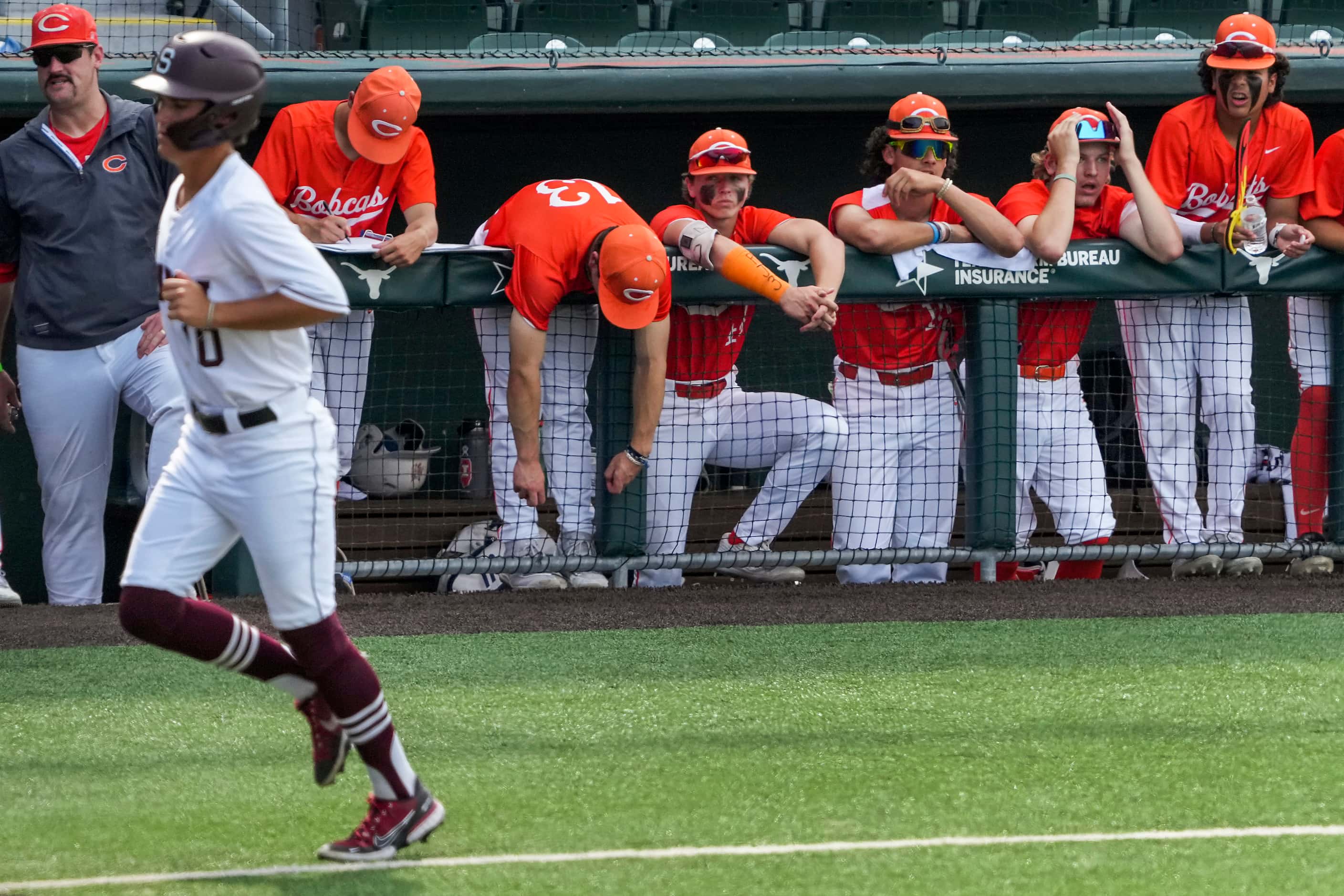 Players in the Celina dugout look on as Sinton baserunner Kline Chester scores on a...