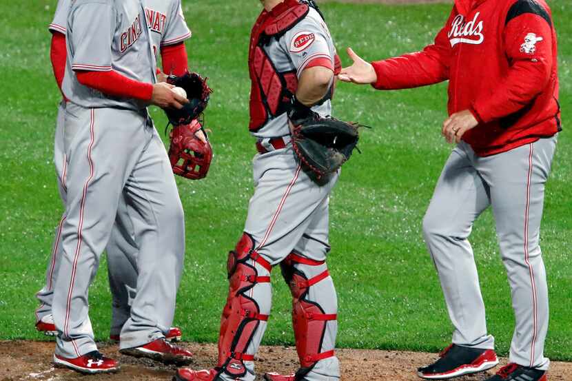 Cincinnati Reds catcher Devin Mesoraco, center, waits as manager Bryan Price, right, takes...