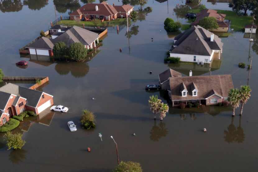 In this aerial photo, homes sit in floodwaters caused Tropical Storm Harvey in Port Arthur,...