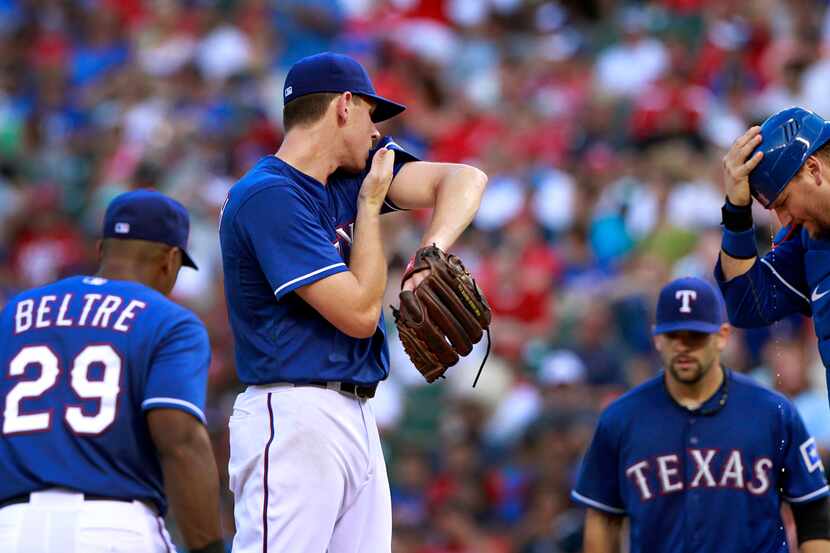 Texas Rangers starting pitcher Nick Tepesch (49) wipes his face as his teammates gather at...