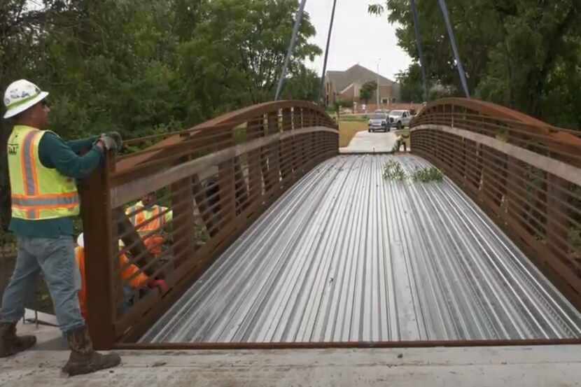 Workers admire one of three new pedestrian bridges that were installed along Legacy Trail in...