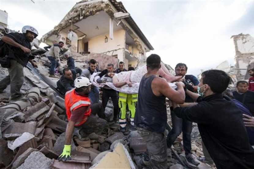 Una mujer es sacada a hombros en una camilla de debajo de los escombros tras el terremoto...