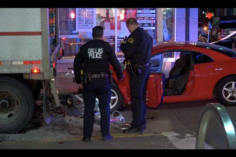 Dallas police look over the scene of a wreck where a delivery driver was pinned against his...